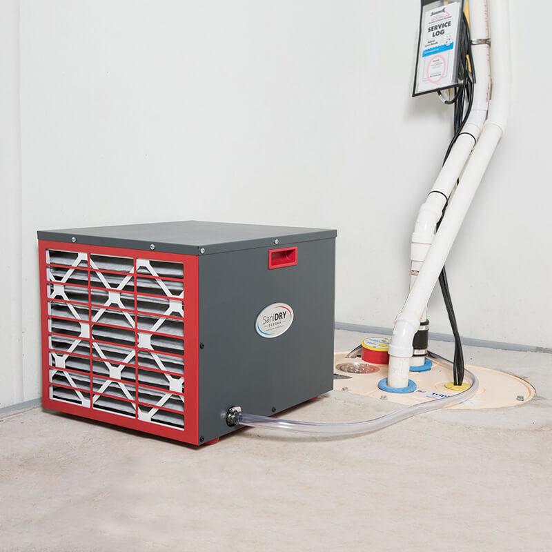 A SaniDry Sedona dehumidifier, TripleSafe Sump Pump and WaterGuard drainage system inside a concrete basement